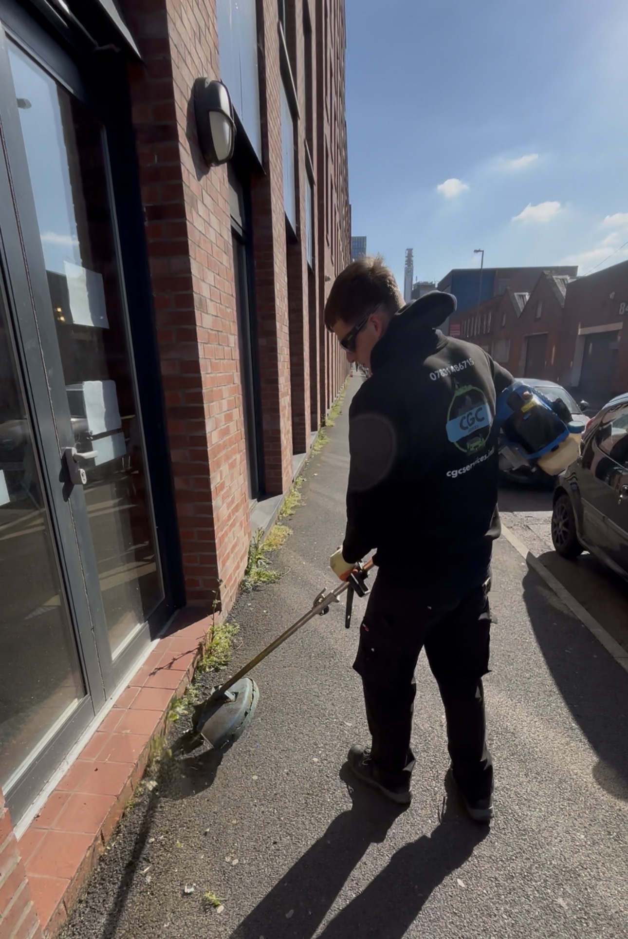 CGC Services team member strimming weeds along a commercial pavement